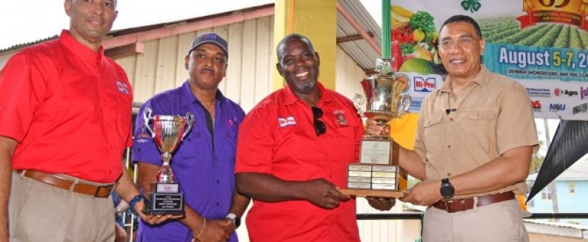 Prime Minister, the Most Hon. Andrew Holness (right), presents the 2023 National Champion Farmer trophy to Managing Director of Unity Boer Goat Farm, Owen Bartley (second right), during the recent staging of the 69th Denbigh Agricultural, Industrial and Food Show at the Denbigh Showground in Clarendon. Sharing the moment (from left) are Vice-President at Hi-Pro, Colonel (Ret’d) Jaimie Ogilvie and Managing Director of the Jamaica Social Investment Fund (JSIF), Omar Sweeney.  
