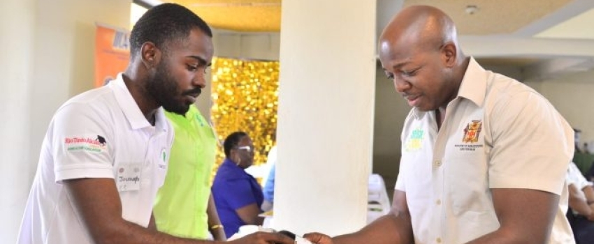 Minister of Agriculture and Fisheries, Hon. Pearnel Charles Jr. (right), is shown a bottle of black castor oil by Jovaughn Bailey of the Jamaica 4-H Clubs, during the Jamaica Bauxite Institute’s (JBI) Castor Industry Forum, dubbed ‘Black Castor Oil - Liquid Gold Untapped’, at the Golf View Hotel in Mandeville, Manchester, on March 15.