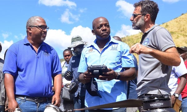 Minister of Agriculture and Fisheries, Hon. Pearnel Charles Jr. (centre), in discussion with Director of Agriculture and Fisheries at Food For the Poor, Nakhle Hado (right), while Chief Strategic Officer, Environmental Solutions Limited, Stephen Jones, looks on. They were in the process of observing a drone (foreground) being used to irrigate an onion farm in St. Thomas, during a tour on Thursday (February 16).
