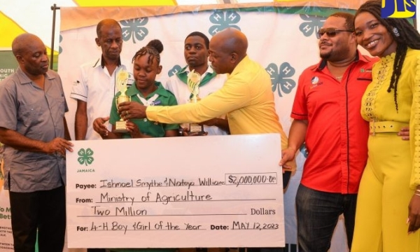 Minister of Agriculture and Fisheries, Hon. Pearnel Charles Jr. (third left), hands the first-place trophy to the 4-H Girl of the Year, Natoya Williams (third right), while Boy of the Year, Ishmael Smythe (fourth right), looks on. The two, who were crowned during the National 4-H Achievement Day Expo at the Denbigh Showground on May 12, also received a monetary prize. Sharing in the moment are (from left) Permanent Secretary in the Ministry of Agriculture and Fisheries, Dermon Spence; Acting Executive Direc