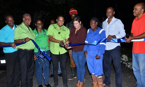 Minister of Agriculture, Fisheries and Mining Hon. Floyd Green (fourth left) cuts the ribbon to officially open a section of the rehabilitated Spring Garden roadway in St. Ann on Wednesday (November 22). He is joined by (from left) Director of Engineering at the Rural Agricultural Development Authority (RADA), Clayton Williams; State Minister in the Ministry of Agriculture, Fisheries and Mining, Hon. Franklyn Witter; Farmer Barbara West; Member of Parliament for North West St. Ann, Krystal Lee; Farmer Jahbl