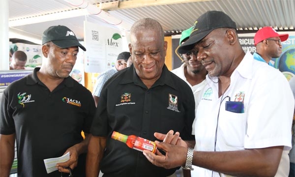 Acting Chief Executive Officer for the Agro-Investment Corporation, Owen Scarlett (right), viewing hot sauce processed by Tijule Company Limited along with Minister of State in the Ministry of Agriculture and Fisheries, Hon Franklin Witter (centre), at the Hague Agricultural and Livestock Show on Wednesday, February 22, 2023. Looking on from left are Director General for the Jamaica Agricultural Commodities Regulatory Authority (JACRA), Peter Thompson, and Immediate Past President of the Trelawny Branch Ass