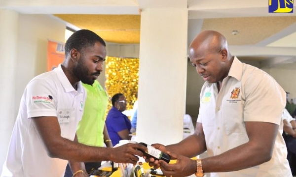 Minister of Agriculture and Fisheries, Hon. Pearnel Charles Jr. (right), is shown a bottle of black castor oil by Jovaughn Bailey of the Jamaica 4-H Clubs, during the Jamaica Bauxite Institute’s (JBI) Castor Industry Forum, dubbed ‘Black Castor Oil - Liquid Gold Untapped’, at the Golf View Hotel in Mandeville, Manchester, on March 15.